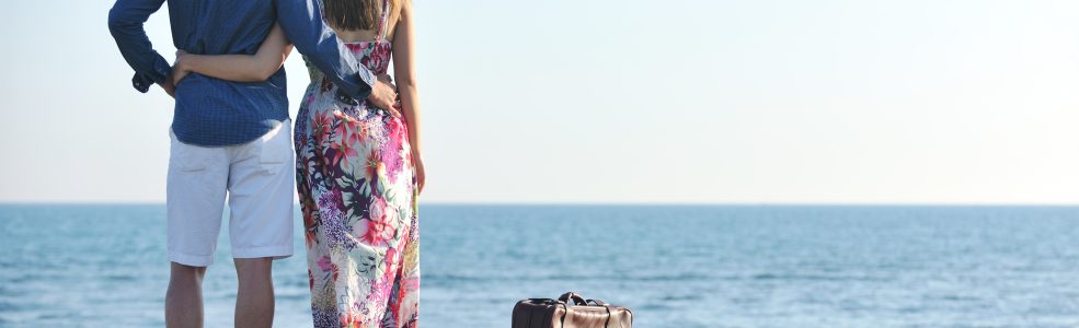 couple on beach with travel bag